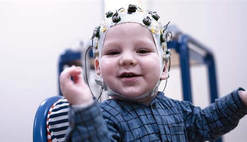 A photo shows a baby fitted with electronic sensors on its head meant to measure brain waves as part of a study on language.