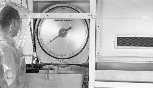 A man in a hazardous material suit stands in front of some industrial material. 