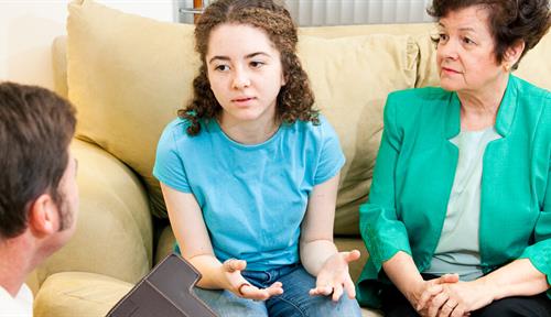 Photograph of a child talking with two adults. Many children help their immigrant family members by acting as language interpreters when dealing with doctors, during business transactions and more.