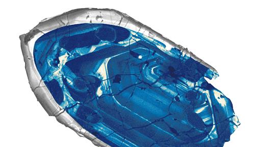 A cross section slice of a fragment of blue crystal edged in translucent gray.