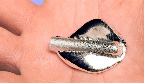 Photo of a person’s palm holding a chunk of silver metal that pools as it melts.