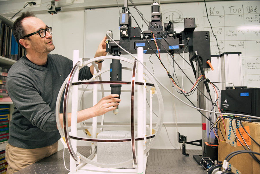 Photograph of a man standing by, and adjusting, a complicated laboratory setup.