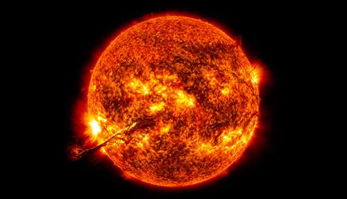 Composite mage shows a solar filament that ribbons from a glowing red sun with areas of yellow eruptions against a black sky.