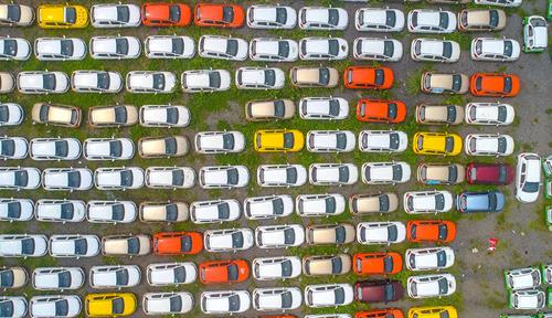 Aerial view of a parking lot crammed with electric cars colored white, tan, yellow and red.