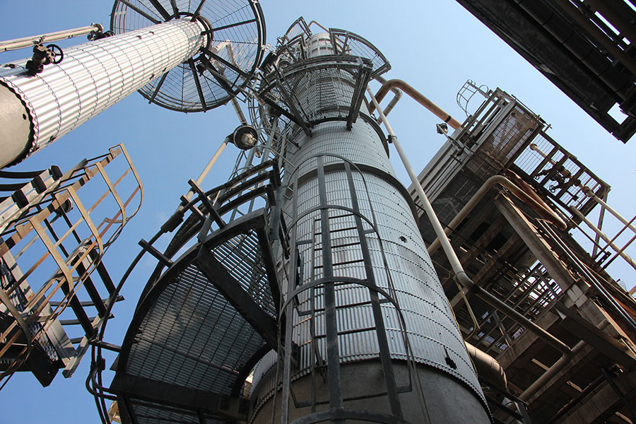 Photograph of towers at a refinery, shot from right below.