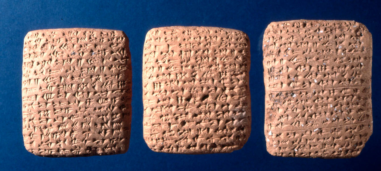 Photograph of three clay tablets covered with cuneiform lettering.