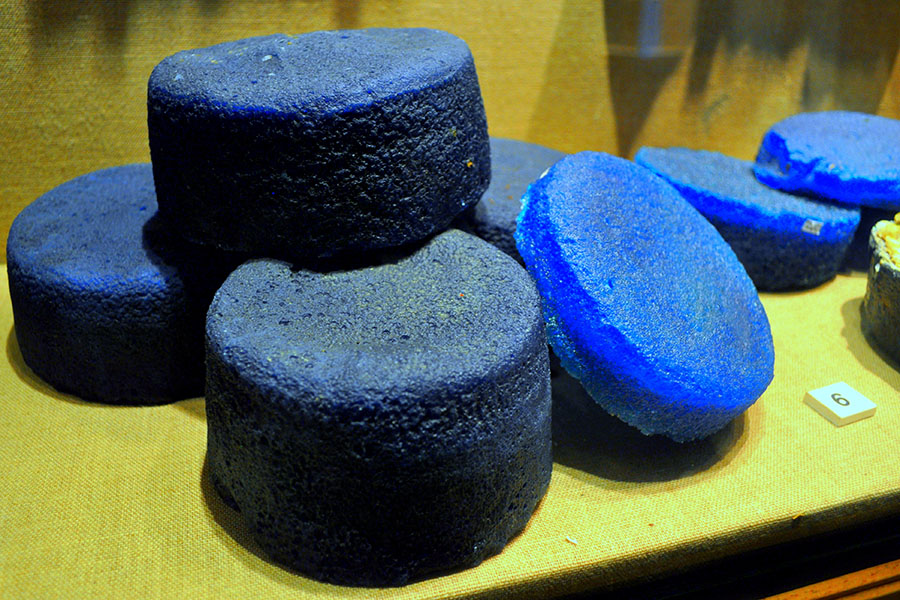 Photograph of about seven fat, blue disks of glass, heaped in a pile.