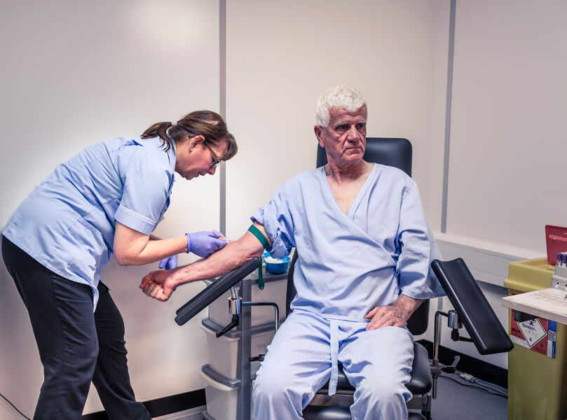 Photograph of a man having his blood drawn by a technician.