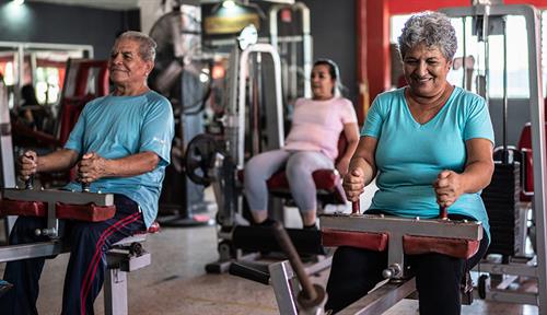 Photograph older adults working out in a gym on exercise machines.