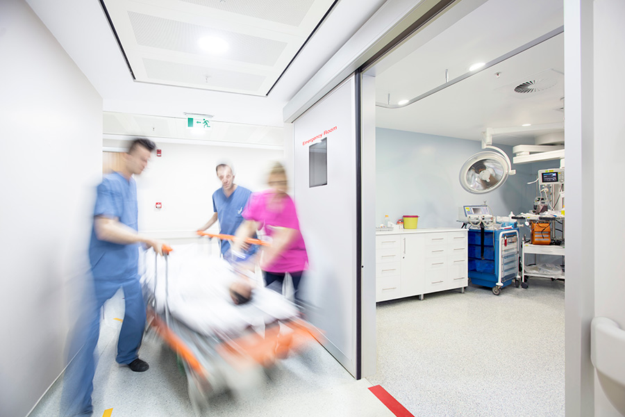 Blurry photo of doctors and nurses wheeling a patient on a gurney in a hospital