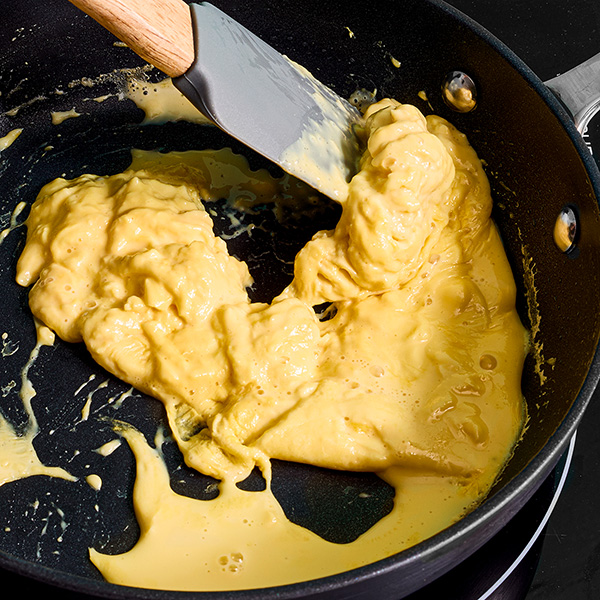 Plant-based eggs being scrambled in a pan.