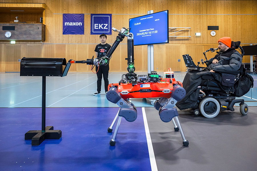 A man in wheelchair uses a breath joystick to guide a robot through a task.