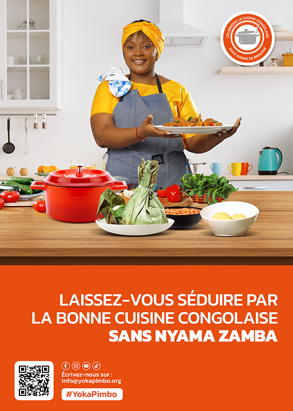 A woman in grey apron and bright yellow headscarf and shirt is smiling behind a counter and holding up a plate of food. Various other vessels of food are displayed on the counter in front of her.