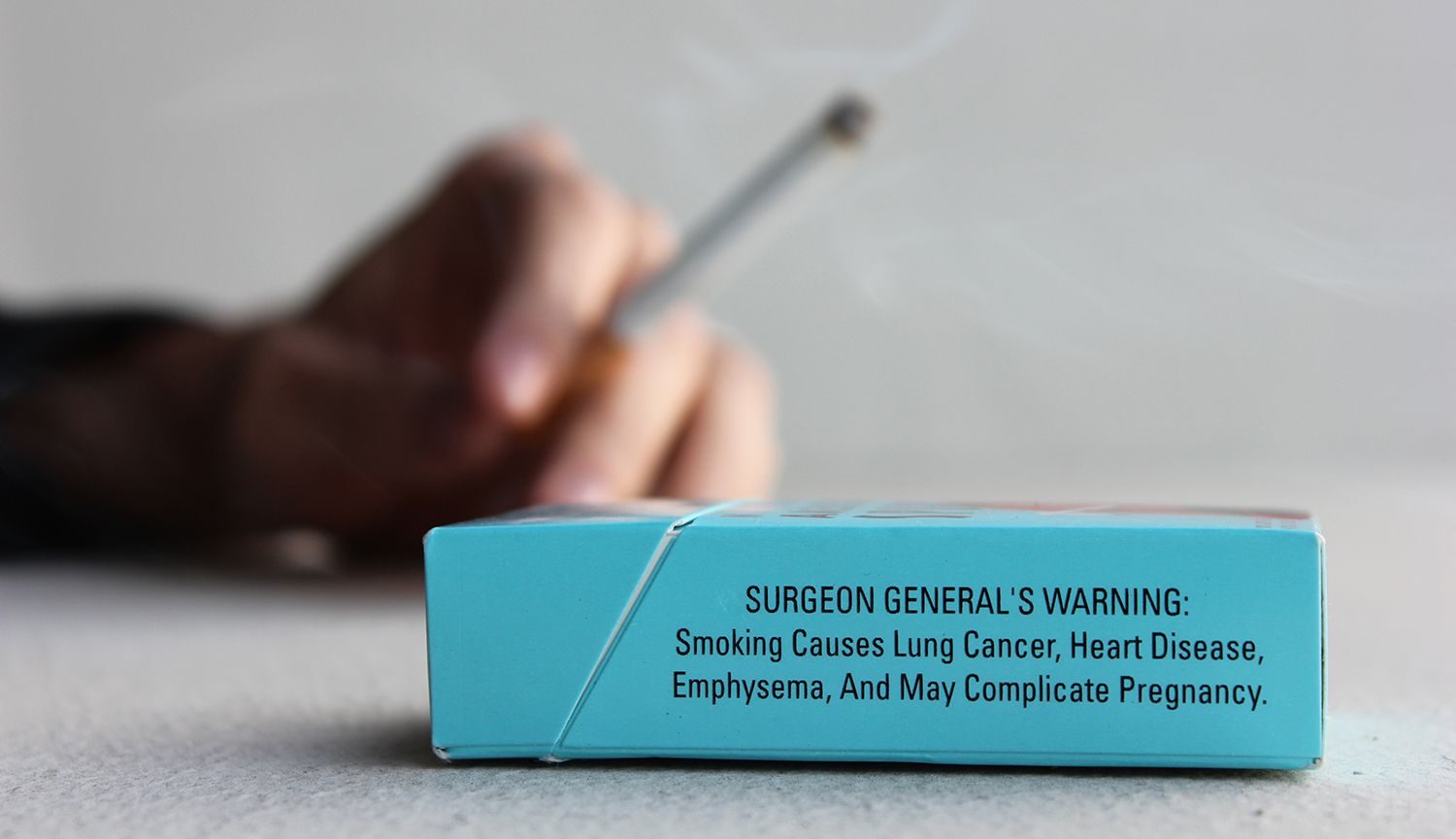 Photograph of a warning label on the side of a cigarette pack. It says SURGEON GENERAL'S WARNING: Smoking Causes Lung Cancer, Heart Disease, Emphysema, And May Complicate Pregnancy.